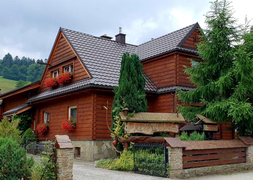 シュチルクにあるPrzybyłówkaの赤い花が咲き誇る大きな木造家屋