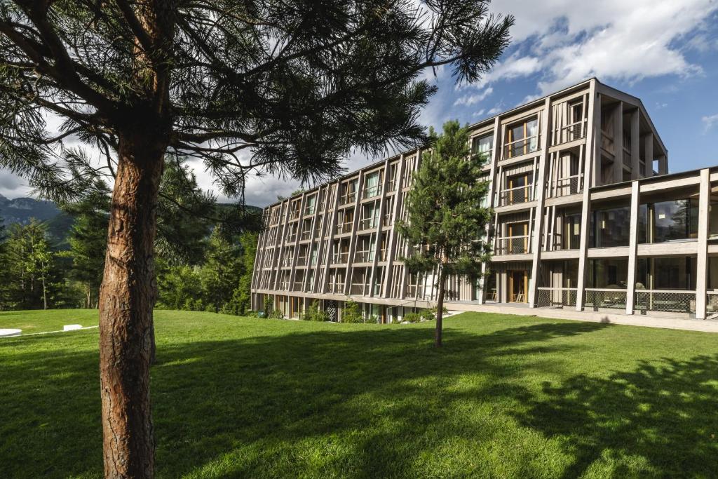 an office building with a tree in front of it at Hotel Bohinj in Bohinj