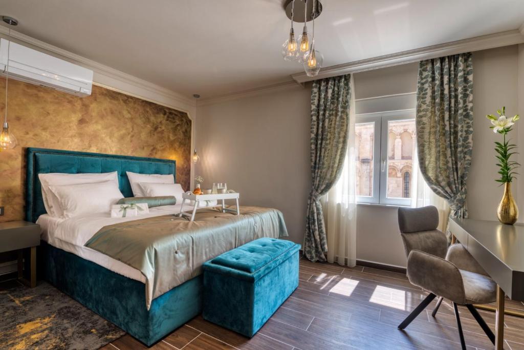 a bedroom with a blue bed and a blue chair at Luxury Rooms VINDEMIÆ in Zadar