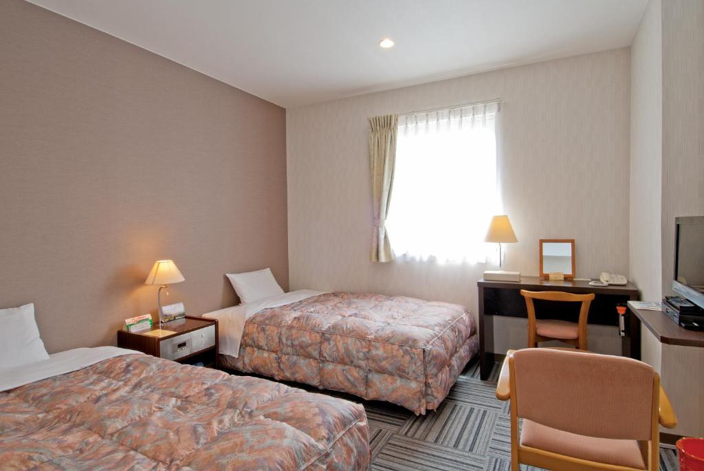 a hotel room with two beds and a desk at Hotel New Ohte in Hakodate