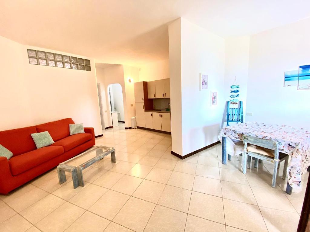 a living room with a red couch and a table at Appartamento Fronte Mare in Santa Teresa Gallura