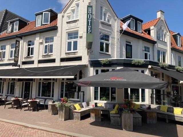 a hotel with tables and an umbrella in front of it at Boutique Hotel de Valk in Valkenswaard