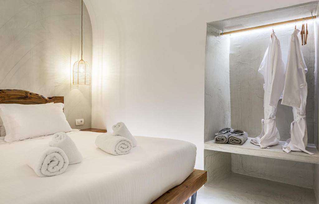 a bedroom with a bed with white sheets and towels at Anila Suites in Fira