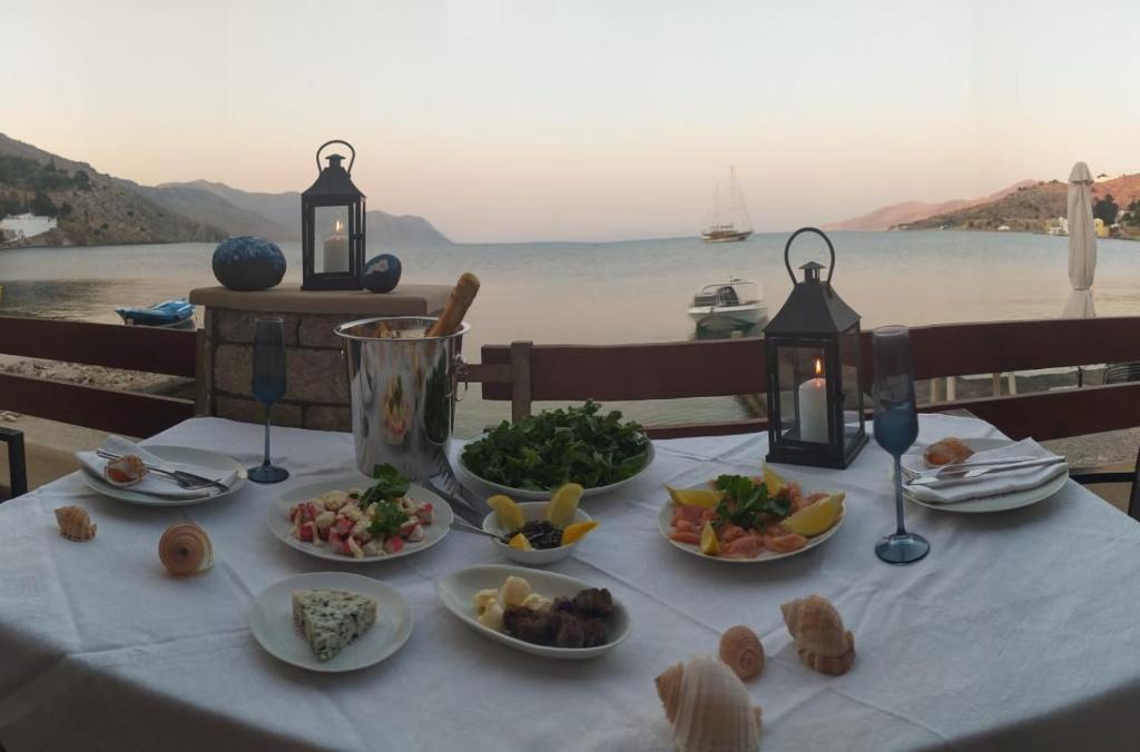 a table with plates of food on it with a view of the water at Symi . VILLA CALME (Sur la Mer). in Symi