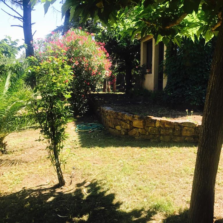 a garden with a stone wall and a house at VILLA EDEN in Figari