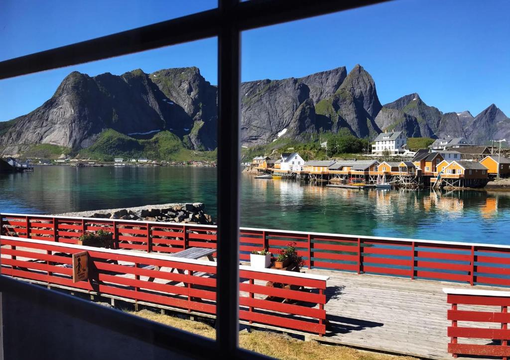 uma vista para a água e para as montanhas a partir de uma janela em Olenilsøy Cabins em Reine