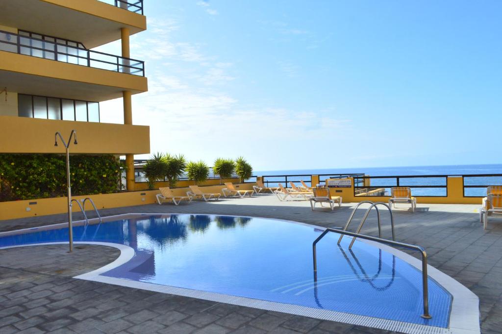 a swimming pool in front of a building with the ocean at Aguamarina 430 in San Miguel de Abona