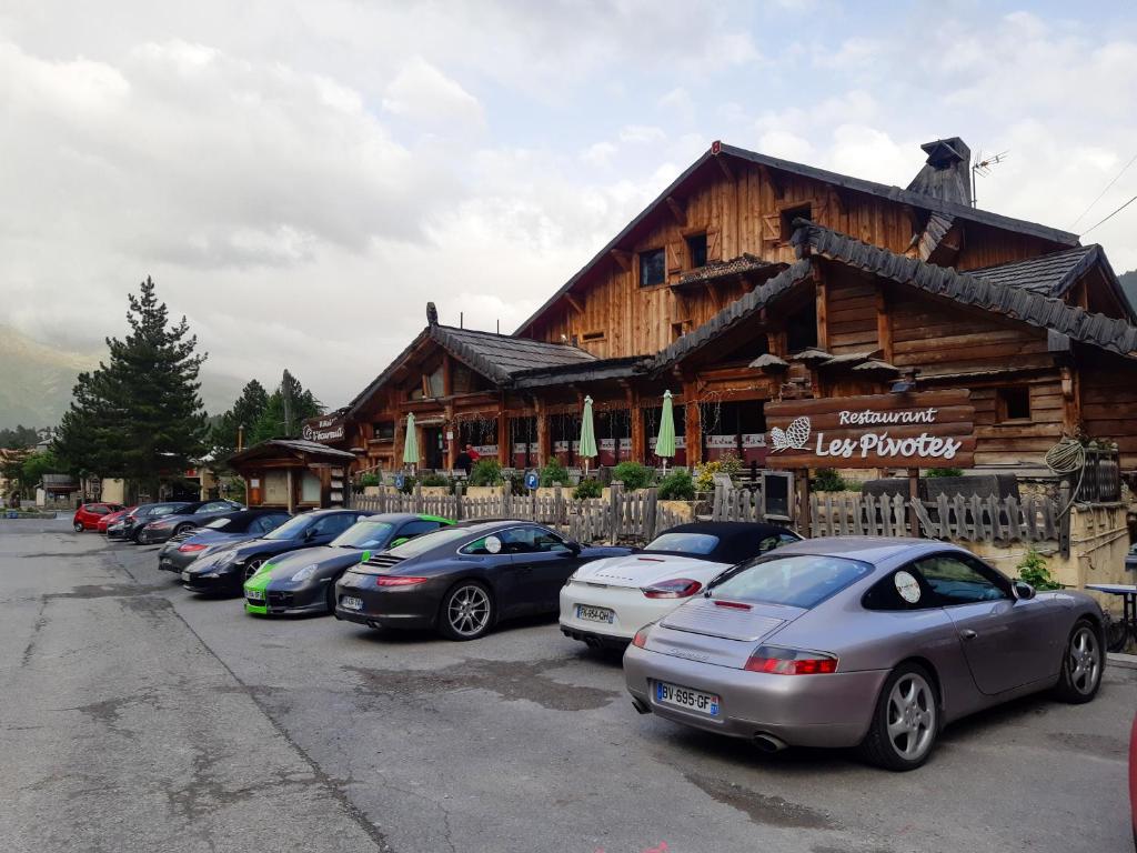 una línea de autos estacionados frente a una cabaña de madera en Hotel l'Ecureuil, en Auron
