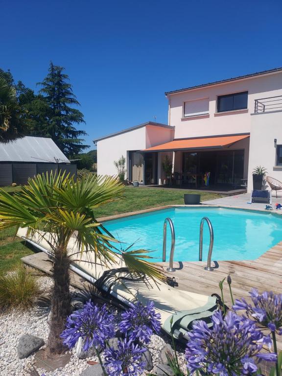 una piscina frente a una casa con flores púrpuras en Maison avec piscine chauffée, en Renac
