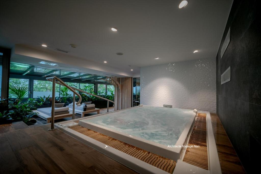 a jacuzzi tub in a room with a large window at Central Park Hôtel & Spa in La Rochelle