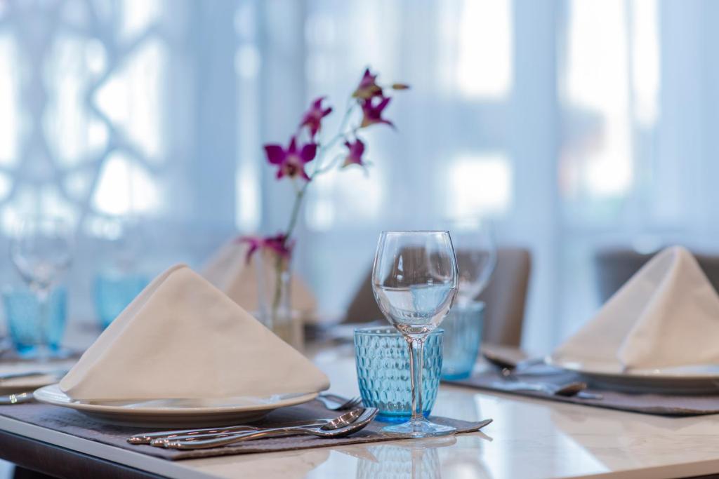a table with a wine glass and plates and napkins at Gardino Hotel & Residence in Riyadh