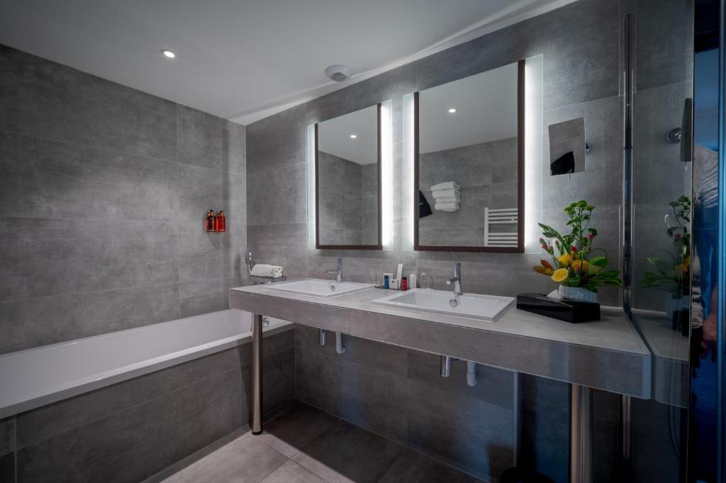 a bathroom with two sinks and a mirror and a tub at Central Park Hôtel & Spa in La Rochelle