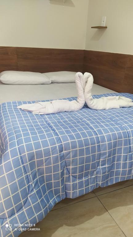 a bed with two white towels on top of it at Pousada Quarto família ar, frigobar,wi fi in Aparecida