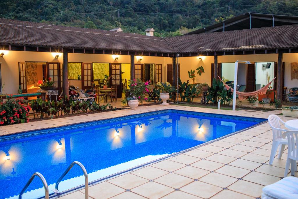 a villa with a swimming pool in front of a house at Pousada Conceito in São Sebastião