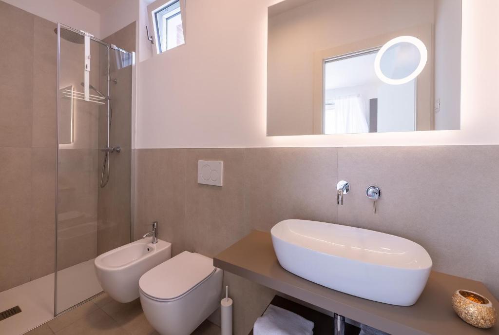 a bathroom with a sink and a toilet and a mirror at Pareus Beach Resort in Caorle