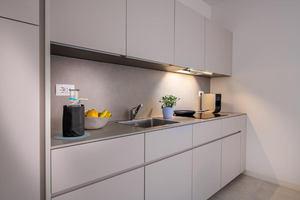 a kitchen with white cabinets and a sink at Pareus Beach Resort in Caorle