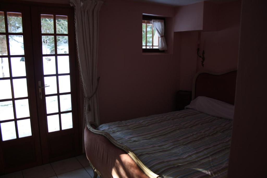 a small bed in a room with two windows at Le Pra d'Alart in La Bollène-Vésubie