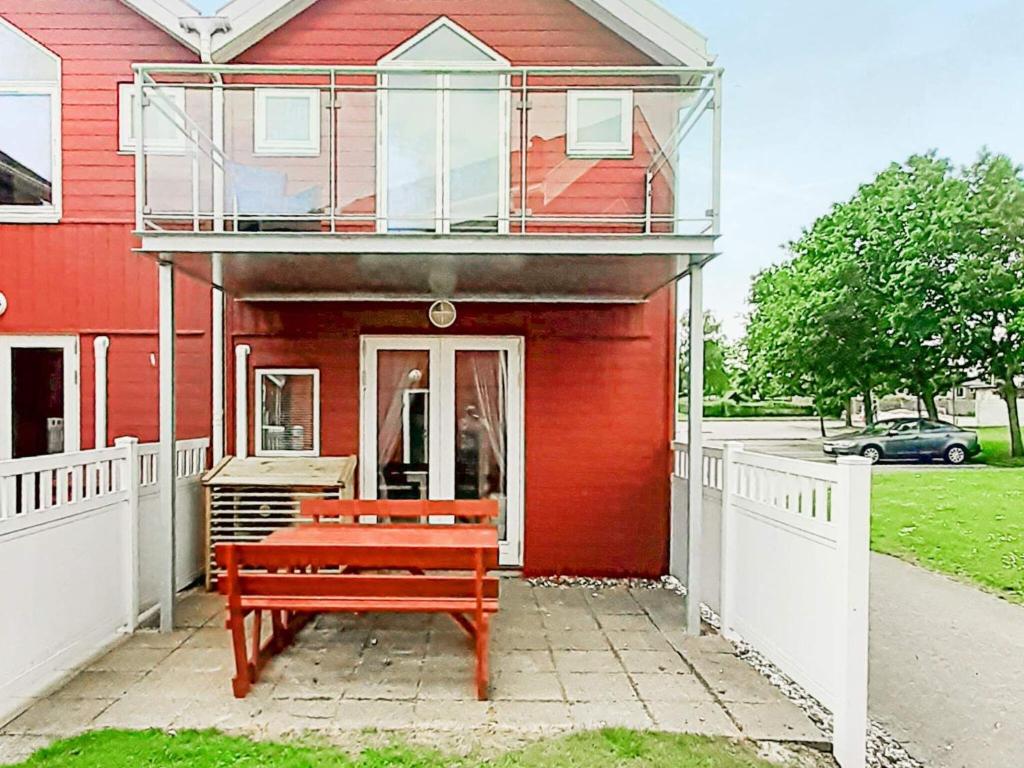 uma casa vermelha com um banco à frente em 6 person holiday home in Hadsund em Hadsund