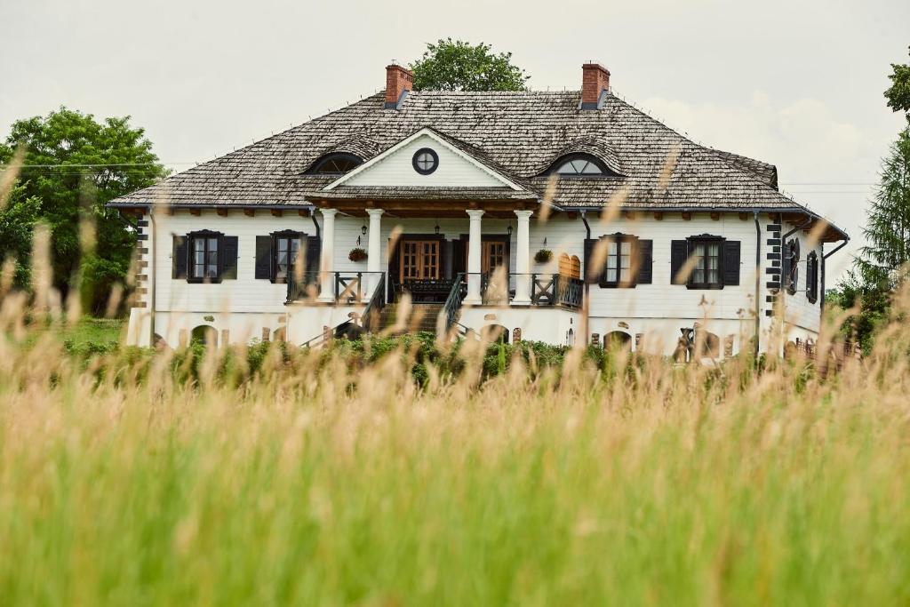 stary dom na polu wysokiej trawy w obiekcie Impresja - pokoje gościnne na nadbużańskich łąkach w mieście Borsuki