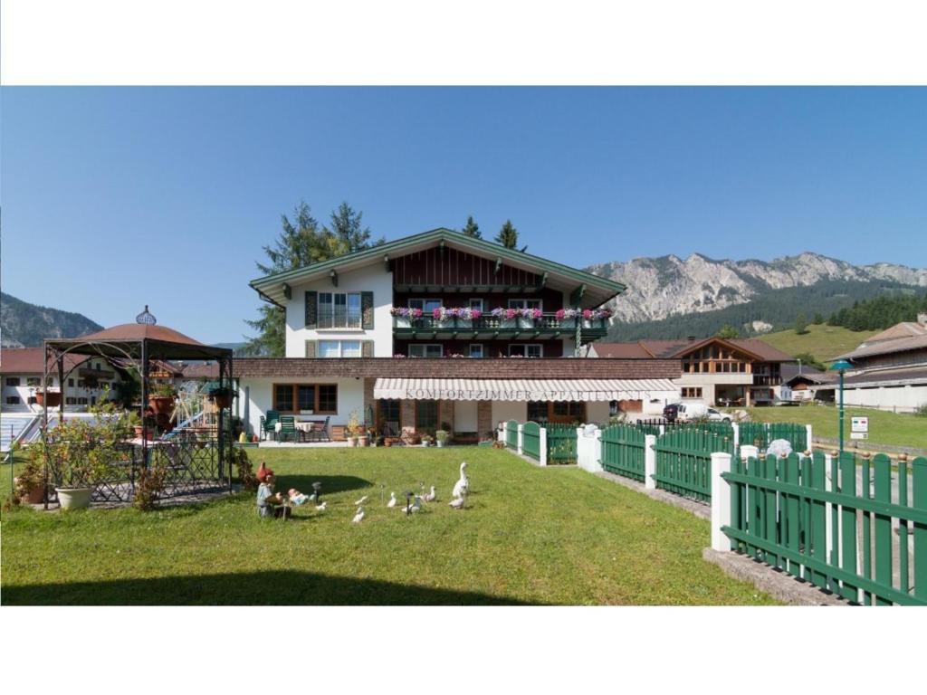 a building with a group of birds in the yard at Gästehaus - Apart Braito in Grän