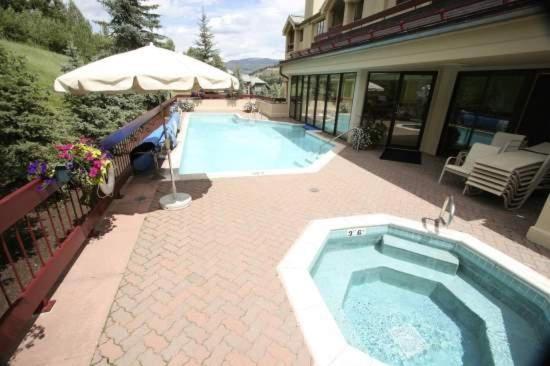 a swimming pool with an umbrella next to a house at Strawberry Park Splendid Slopes View in Beaver Creek