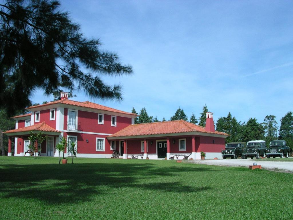 Casa roja y blanca con un gran patio en Casa da Ria - Turismo Rural, en Ílhavo