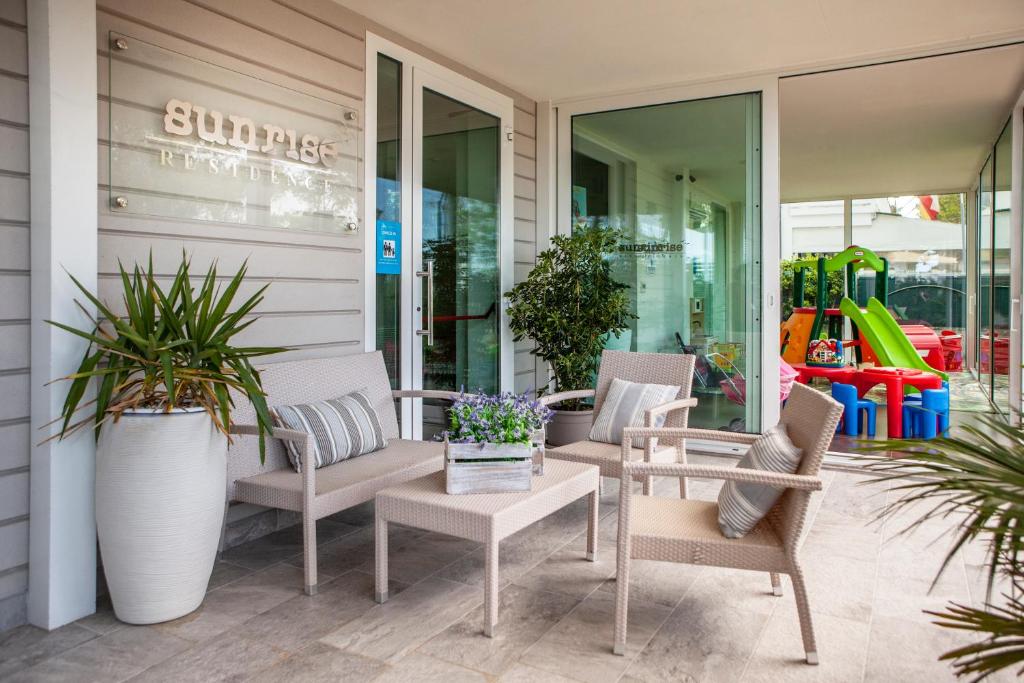 eine Terrasse mit Stühlen, einem Tisch und einem Spielplatz in der Unterkunft Residence Sunrise Cesenatico in Cesenatico
