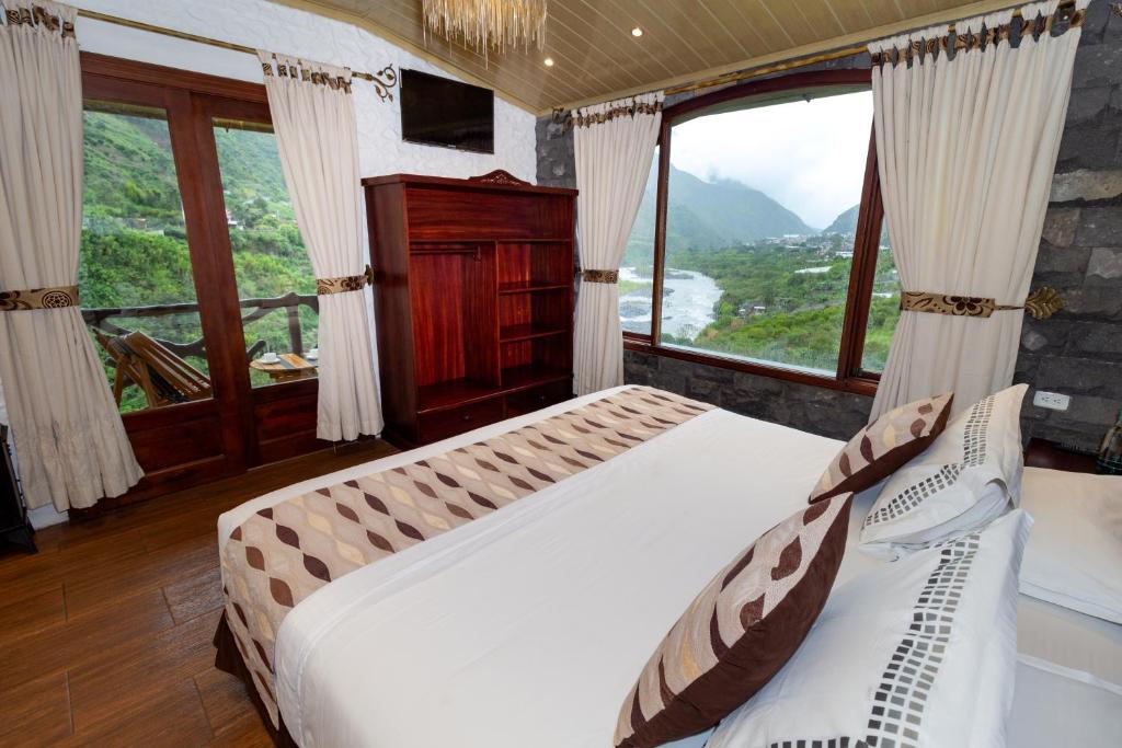 a bedroom with two beds and a large window at Aldea Real Eco Friendly in Baños