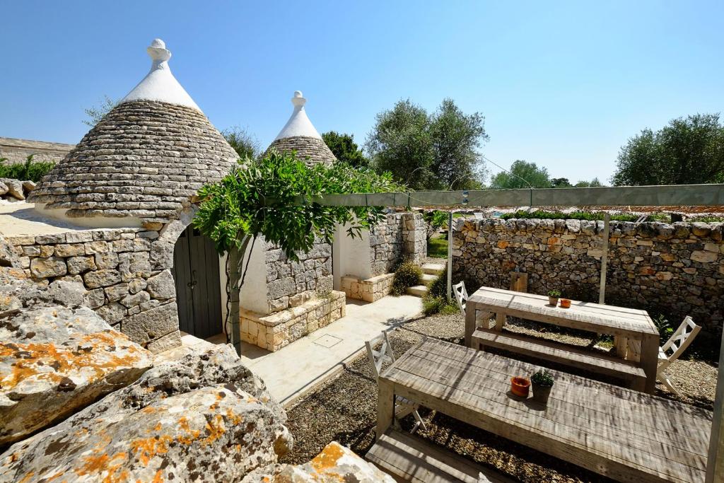 a stone building with a bench and a table at Masseria Trulli e Vigne in Martina Franca