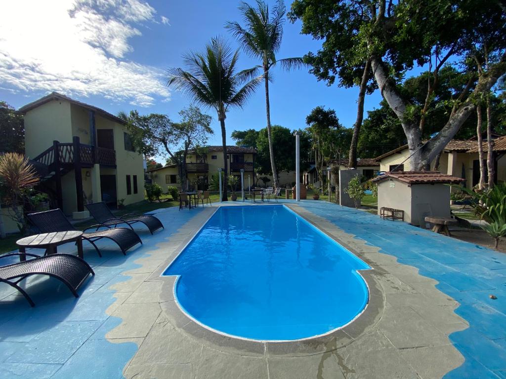 a large swimming pool with lounge chairs and trees at Pousada Casa de Maria Bonita in Arraial d'Ajuda