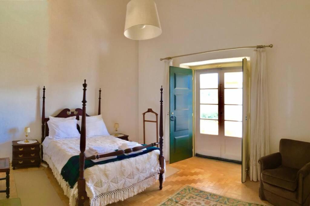 - une chambre avec un lit et une porte coulissante en verre dans l'établissement Casa da Praia do Ribatejo - Casa da Arcada, à Praia do Ribatejo