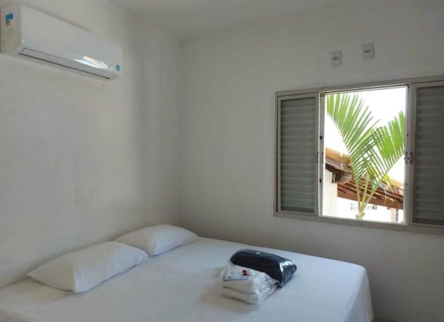 uma cama branca num quarto com uma janela em Pousada Escarpas em Capitólio