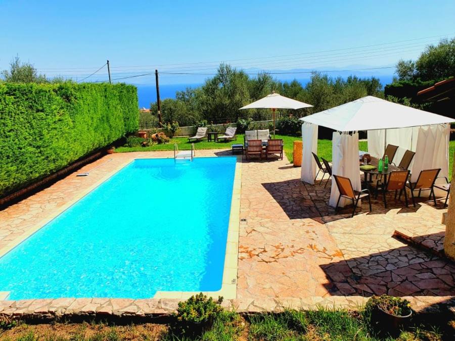 een zwembad met een tafel en stoelen en een parasol bij Platanos Estate in Akrata