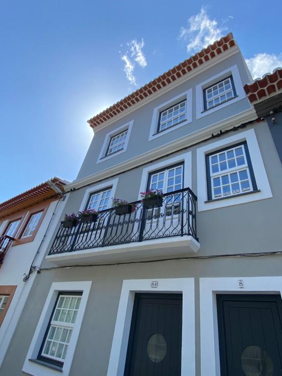 ein weißes Gebäude mit einem Balkon und einem blauen Himmel in der Unterkunft Casas do Mercado - Casa Orion in Angra do Heroísmo