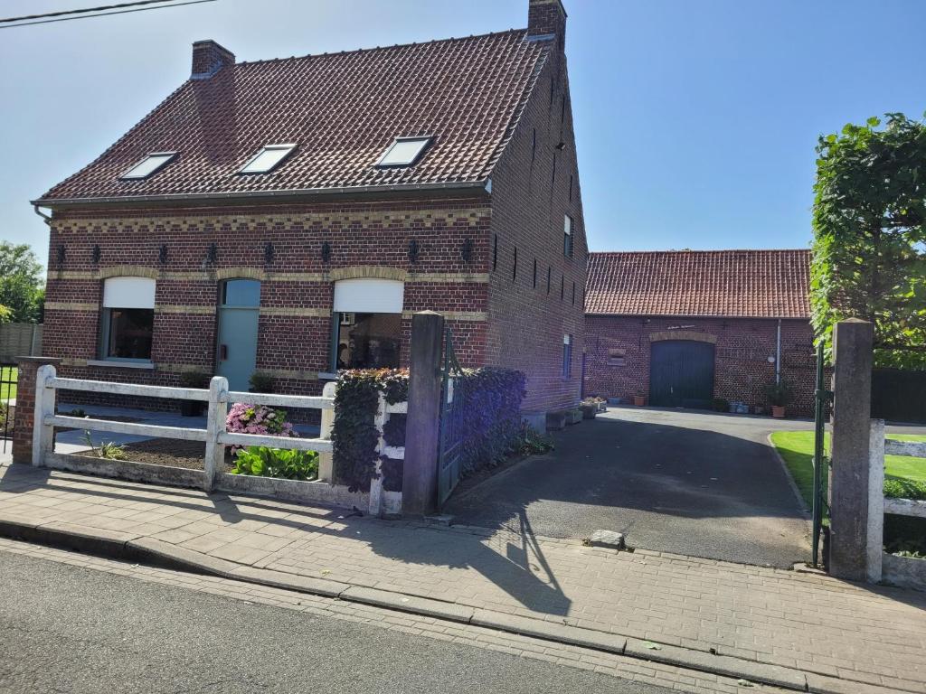 una casa de ladrillo con una valla blanca en una calle en vakantiewoning hoeve 'd oude scheure, en Kortemark