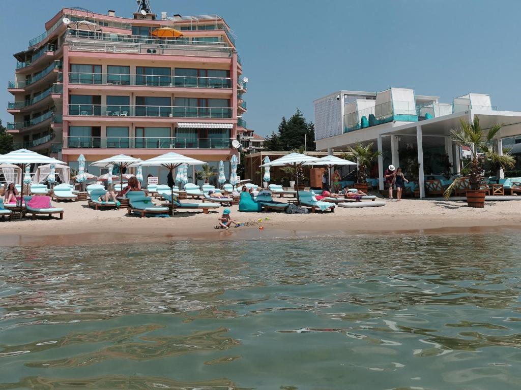 ein Strand mit Stühlen und Sonnenschirmen sowie ein Gebäude in der Unterkunft Beachfront Smart Homes by Marty's in Sonnenstrand