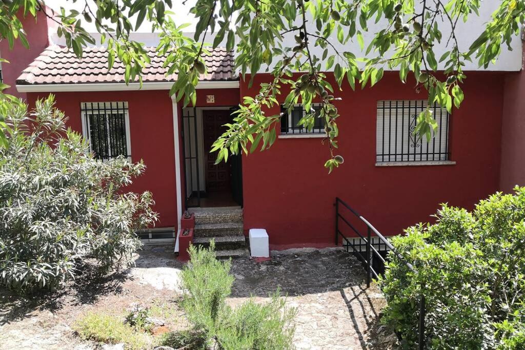 una casa roja con escaleras que conducen a la puerta principal en Susan Home, en San Martín de Valdeiglesias