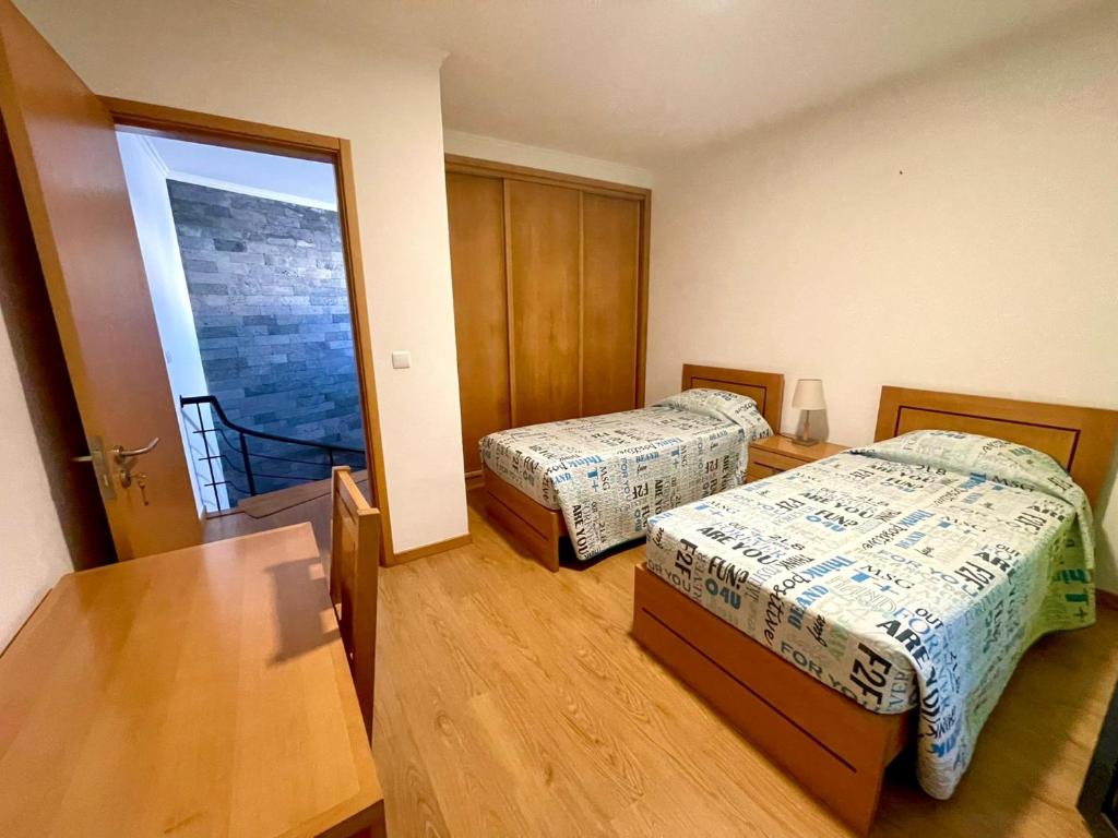 Una habitación con dos camas y una mesa y una ventana. en Casa Brisa do Mar, en Ponta Delgada