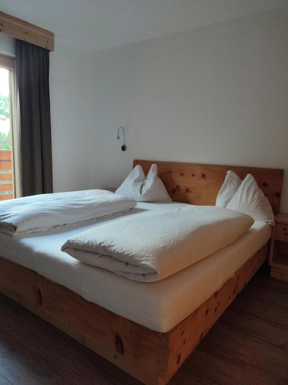 um quarto com uma cama de madeira e lençóis brancos em Apartments B&B Pretermo em Badia