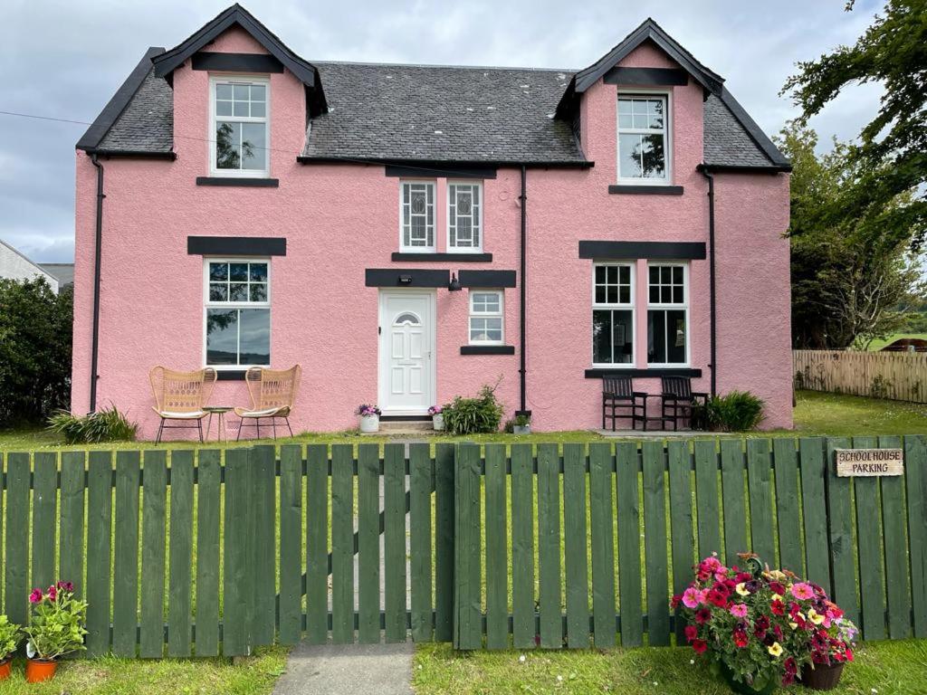 uma casa cor-de-rosa com uma vedação à frente. em Arran School House - Blackwaterfoot, Isle of Arran em Blackwaterfoot