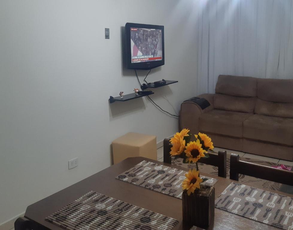 uma sala de estar com um sofá e uma mesa com flores em Apartamento Guaruja Enseada 2 Quadra da Praia Atrás do Aquario no Guarujá