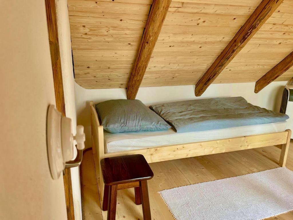 małe łóżko w pokoju z drewnianym sufitem w obiekcie Apartmány pod Kozákem w mieście Velké Popovice
