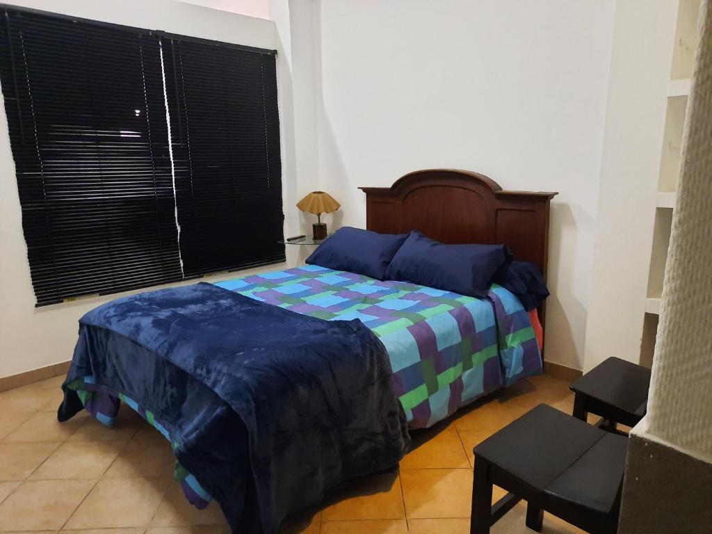 a bedroom with a bed with a blue and green blanket at DEPARTAMENTO COSTANERA in Corrientes