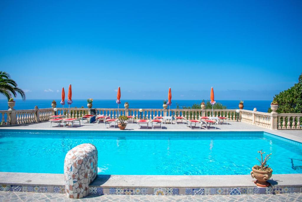 a swimming pool with tables and chairs and the ocean at Hotel Villa Rita in Ischia
