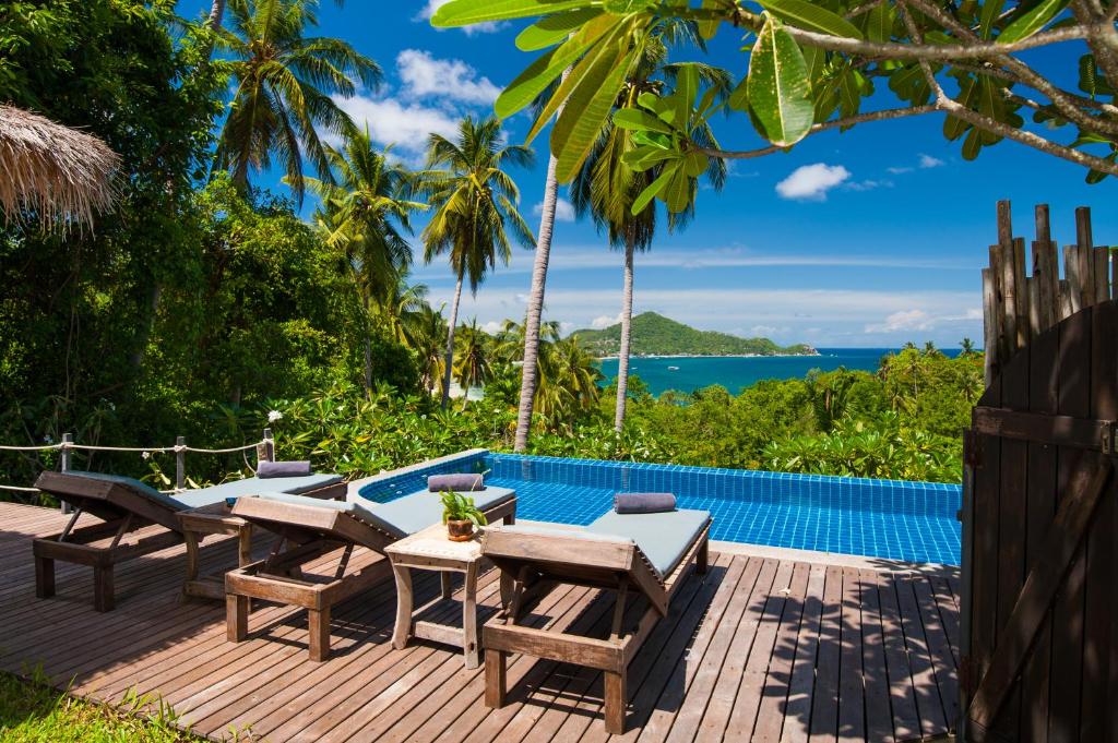 a deck with a table and chairs next to a swimming pool at Koh Tao Heights Boutique Villas in Ko Tao