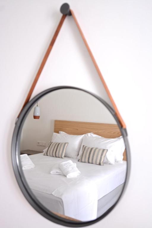 a mirror reflecting a bed with white sheets and pillows at Pénde Suites in Livadion