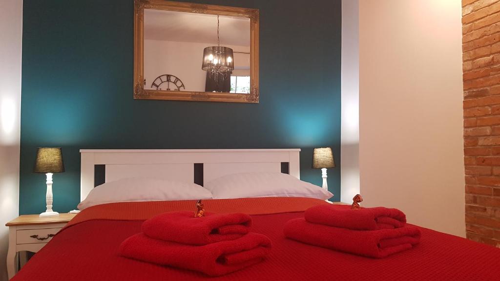 - une chambre avec un lit rouge et 2 serviettes dans l'établissement H&T Old Town Szeroka 36, à Gdańsk