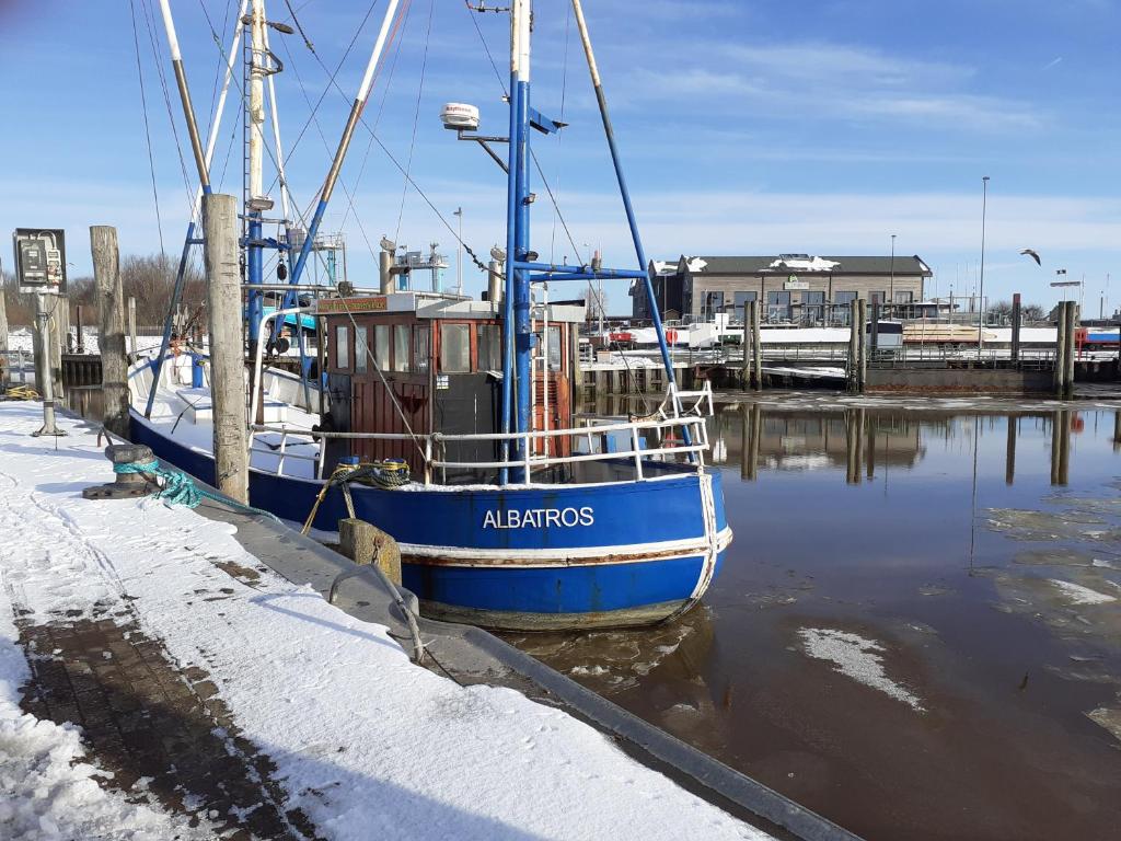 ein blaues Boot an einem Dock im Wasser angedockt in der Unterkunft Fahrradurlaub in Ostfriesland für 4 Personen in Utarp