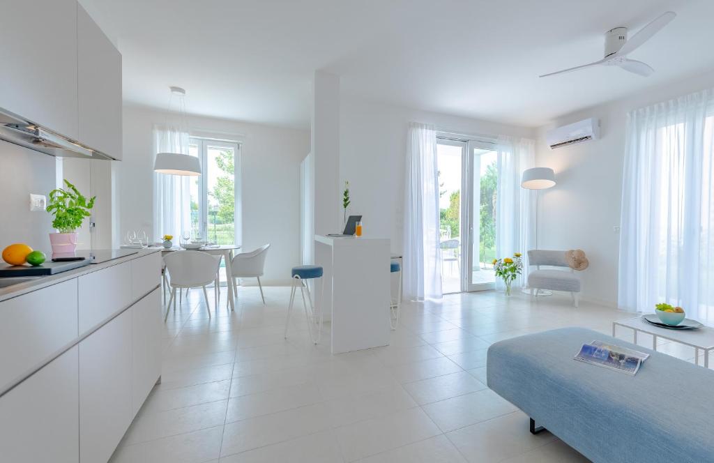 a white kitchen and living room with a blue couch at Pareus Beach Resort in Caorle