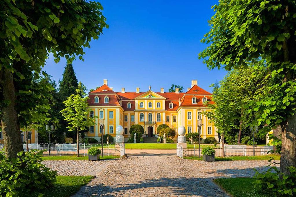 ein großes gelbes Haus mit rotem Dach in der Unterkunft Barockschloss Rammenau in Rammenau